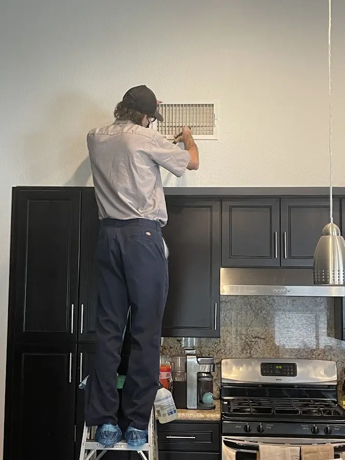 Technician inspecting an air vent during HVAC service in Pecan Grove